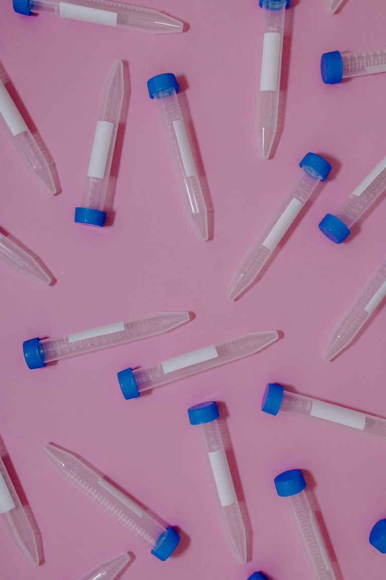 Dynamic flat lay of medical test tubes scattered on a pink surface, creating a vibrant contrast.