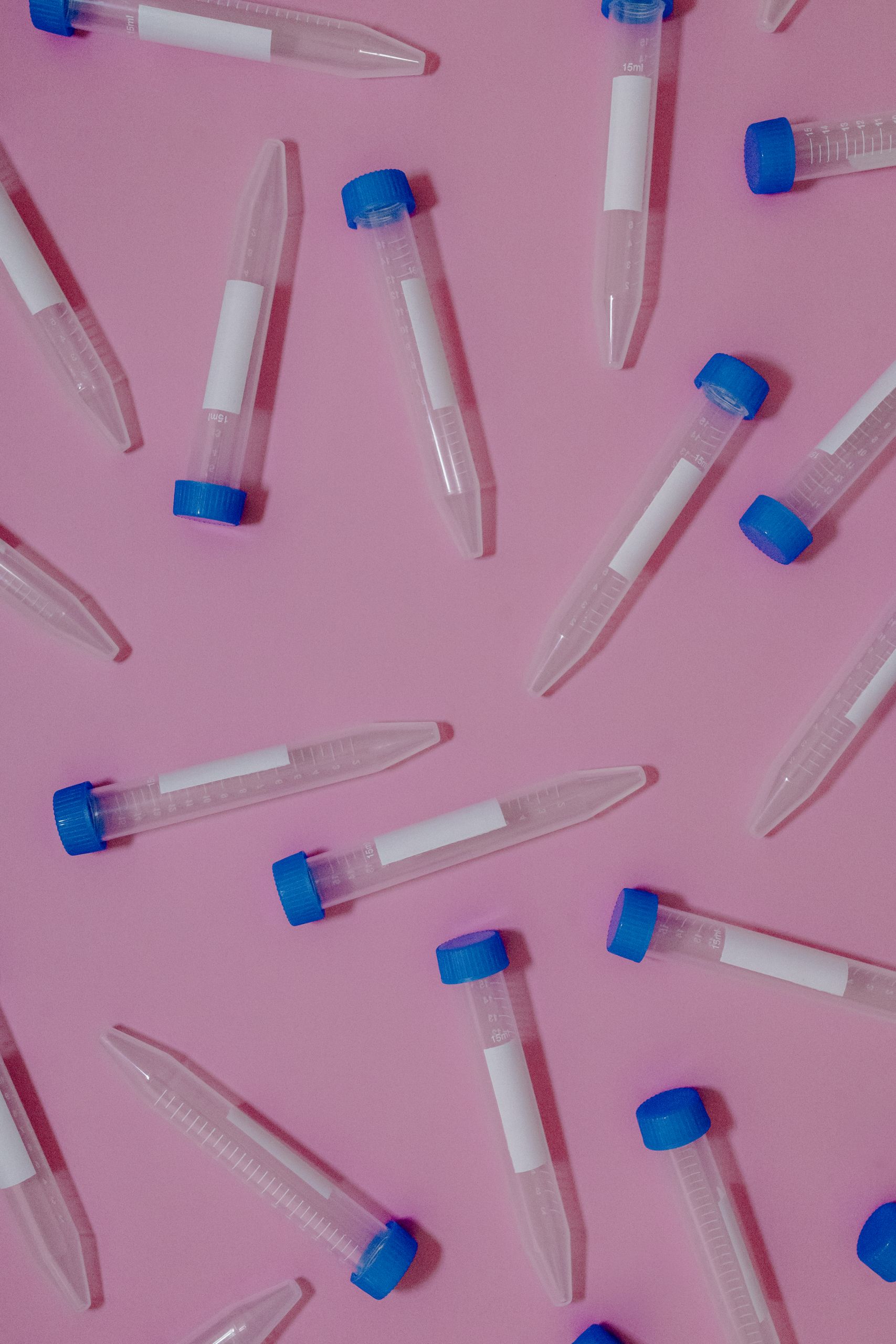 Dynamic flat lay of medical test tubes scattered on a pink surface, creating a vibrant contrast.